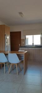 a kitchen with a wooden table and white chairs at Dpto Sarmiento Centro in San Juan