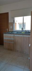 a kitchen with wooden cabinets and a sink and a window at Dpto Sarmiento Centro in San Juan