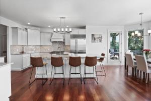 a kitchen with white cabinets and a table with bar stools at Luxurious Mansion, Deck, Patio, Chef’s Kitchen in Crown Point +51 photos