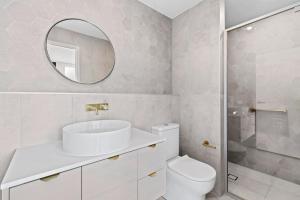 a bathroom with a sink and a toilet and a mirror at Ohana Apartments 103 in Batemans Bay