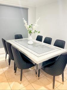 una mesa de comedor con sillas y un jarrón con flores en Luxurious Family Home en Sydenham