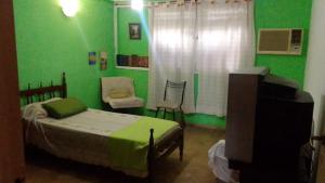 1 dormitorio con cama y pared verde en La Cage en San Miguel de Tucumán