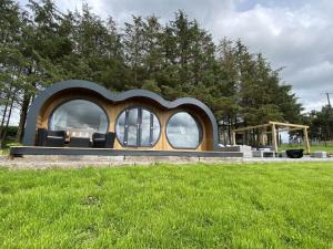 a house in a field with trees in the background at Great House Farm Luxury Pods and Self Catering in Crickadarn