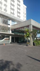 a large white building with palm trees in a parking lot at Apartemen Malioboro city by Ameliarooms in Yogyakarta