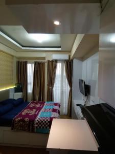 een slaapkamer met een bed en een televisie en een tafel bij Apartemen Malioboro city by Ameliarooms in Yogyakarta