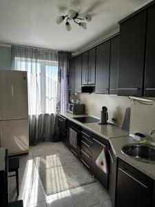 a kitchen with black cabinets and a refrigerator at Apartment on Agrba in Pizunda