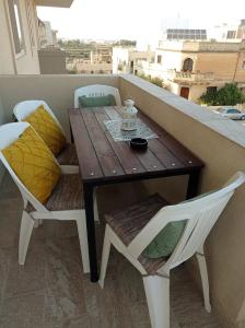 y balcón con mesa y sillas de madera. en "Joseph 2" Stylish corner flat with open views, just 5km from the beach en Siġġiewi