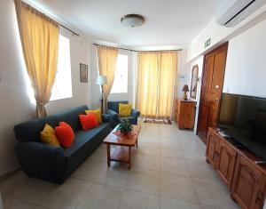 sala de estar con sofá azul y TV en "Joseph 2" Stylish corner flat with open views, just 5km from the beach, en Siġġiewi