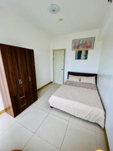 een slaapkamer met een bed en een houten kast bij Luxury Two Bedroom with Balcony in SOUTH RESIDENCE of Las Pinas in Manilla
