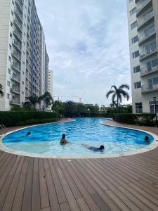 two people swimming in a large swimming pool with buildings at Luxury Two Bedroom with Balcony in SOUTH RESIDENCE of Las Pinas in Manila