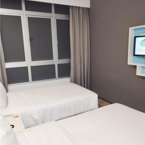 a bedroom with two beds and a tv on a wall at Room in Genting Highland in Genting Highlands