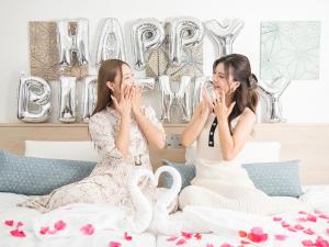 two women sitting on a bed with champagne glasses at Vessel Inn Sakae Ekimae in Nagoya