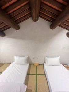 two beds in a room with wooden ceilings at 壹樓文旅 in Jinhu
