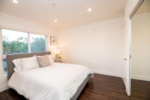 a white bedroom with a large bed and a window at Luxury 2Bed/2Bath Apt in West Hollywood w/ Rooftop in Los Angeles