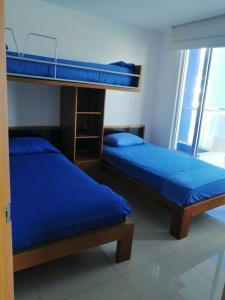 2 literas con sábanas azules en una habitación en Lujoso Condominio Frente al Mar en Tonsupa, Ecuador, en Tonsupa
