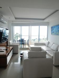 Sala de estar blanca con sofás blancos y mesa en Lujoso Condominio Frente al Mar en Tonsupa, Ecuador, en Tonsupa