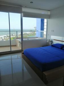 1 dormitorio con 1 cama azul y ventanas grandes en Lujoso Condominio Frente al Mar en Tonsupa, Ecuador, en Tonsupa