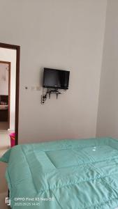 ein Schlafzimmer mit einem Bett und einem TV an der Wand in der Unterkunft Jatisela Homestay5 in Midang