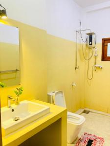 a yellow bathroom with a sink and a toilet at Villa bodhi Ahangama, Home stay in Ahangama
