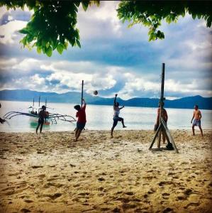 a group of people playing volleyball on the beach at Port Barton Island Camping in San Vicente