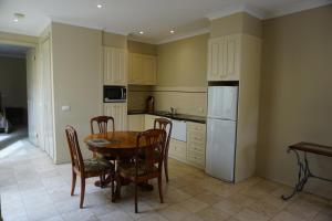 a kitchen with a table and chairs and a refrigerator at Acacia Terraces in Echuca