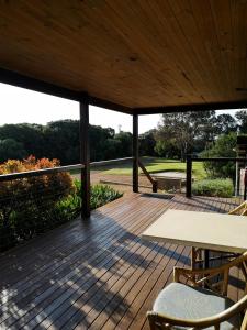 una terraza de madera con mesa y sillas. en Karriview, en Gracetown