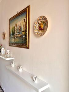 ein Gemälde an einer Wand mit zwei weißen Regalen in der Unterkunft Casa vacanza Salento, Santa Maria al Bagno in Galatone