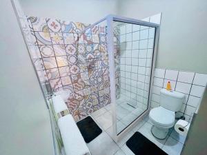 a bathroom with a toilet and a shower with a mosaic wall at Madeira Bed in Queenstown