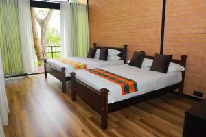 two beds sitting in a room with a window at Life of Leisure Wilpattu in Pahala Maragahawewa