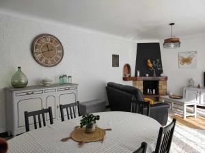 a living room with a table and a clock on the wall at Villa des petites Chaumes in Avallon