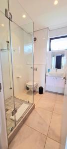 a bathroom with a glass shower and a toilet at Zimbali Lakes Boulevard Suites in Ballito