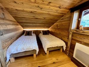 two beds in a log cabin bedroom at Appartement cosy vue montagne in La Clusaz