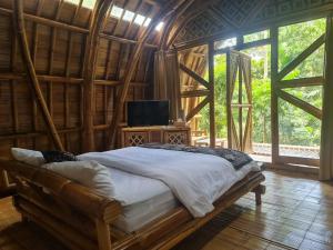 a bedroom with a bed in a room with windows at The Osing Bamboo Resort - a LIBERTA Collection in Banyuwangi