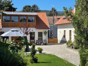 a white house with an umbrella and a courtyard at Kis-Duna Vendégház in Dunabogdány