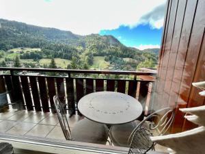 a table and chairs on a balcony with a view at Appartement cosy vue montagne in La Clusaz