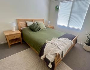 ein Schlafzimmer mit einem grünen Bett und einem Fenster in der Unterkunft Copper Shores Holiday House in Wallaroo