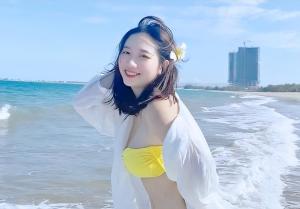 a woman in a yellow and white bikini on the beach at La Maison Danang Beach Hotel in Da Nang