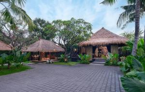 a resort with two huts and palm trees at The One Boutique Villa in Seminyak