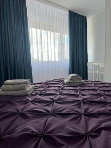 a purple bed with towels on top of it at EVA's Rooms in Târgu-Mureş