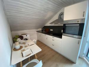 a small kitchen with white cabinets and a table at Charmantes Apartment mit Balkon in Mindelheim