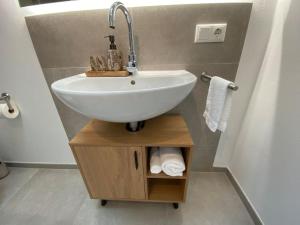 a bathroom with a sink and a shelf with towels at Charmantes Apartment mit Balkon in Mindelheim
