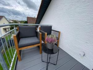 a balcony with two chairs and a table with flowers at Charmantes Apartment mit Balkon in Mindelheim