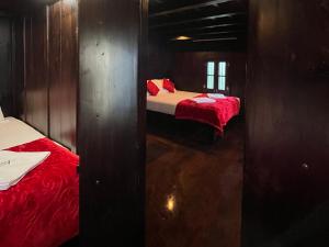 two beds in a small room with red sheets at Nature Castle in Kottakamboor