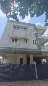 uma grande casa branca com uma cerca em frente em Shantham Service Apartments, Indumanagar, Coimbatore em Coimbatore