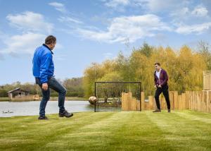 dwóch mężczyzn grających w piłkę nożną w trawie w obiekcie Noahs Retreat w mieście Laceby