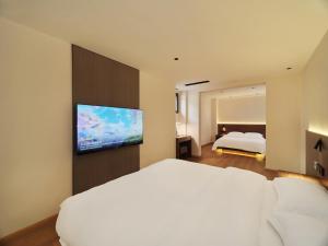 a bedroom with a white bed and a flat screen tv at Xilu Xiaoxie Inn in Lijiang