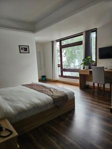 a bedroom with a bed and a desk and a window at Shanol Residency in Gangtok