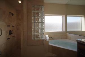 baño con bañera y ducha con ventana en GOLF HUB- Luxurious Mansion 14 bed/6 Bath 6k sq ft, en Mesquite