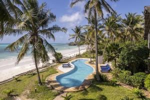 a resort pool with palm trees and the beach at Dar Beach House - Michamvi in Michamvi