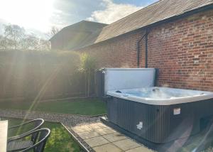 a hot tub sitting next to a brick building at Haveringland Hall in Cawston